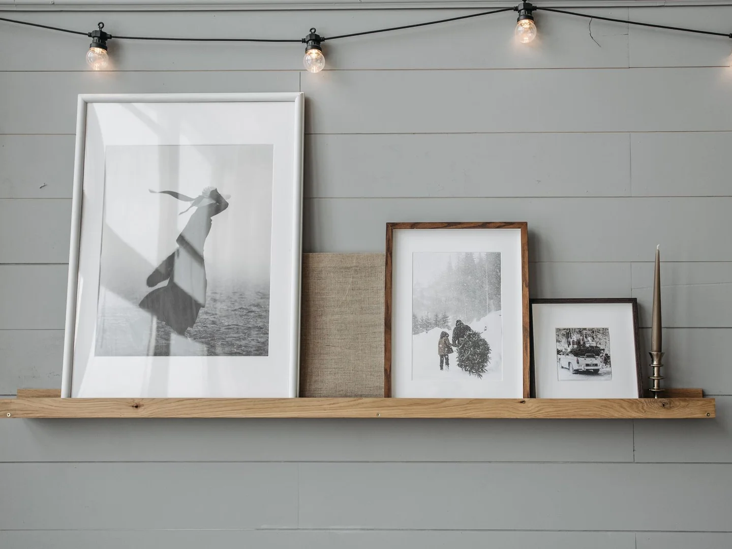 Wood-framed black and white prints resting on a narrow wall shelf.