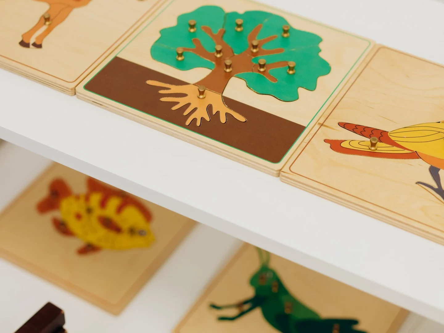 Wooden children's puzzles stored together on a low shelf.