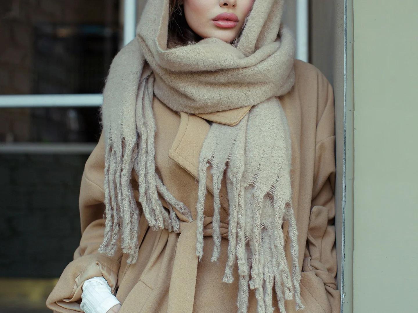 A neutral scarf worn with a beige coat.