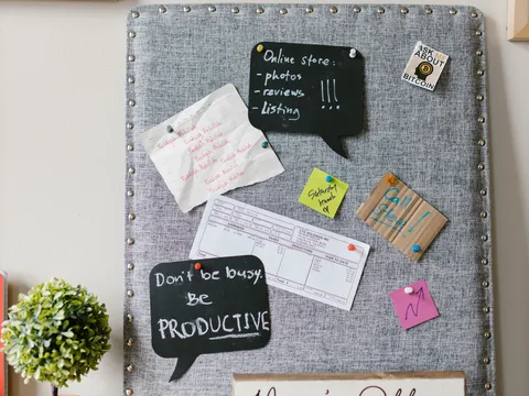 Paper notes clipped to a gray fabric-covered noticeboard.