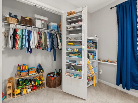 Children's clothes and storage containers arranged in a closet.