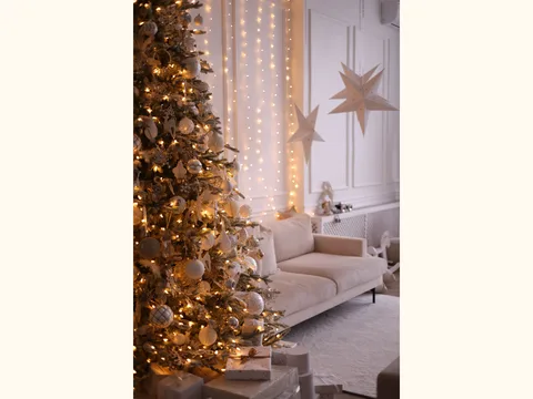A Christmas tree standing beside a sofa in a living room.