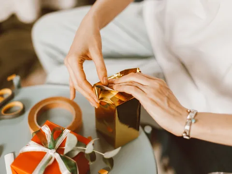 Gift boxes being wrapped on a work surface.