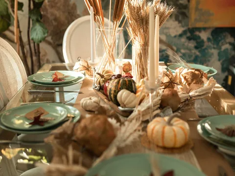 An autumn table setting with small pumpkins and candles.
