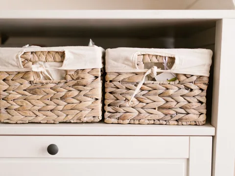 Woven storage baskets with handles arranged on shelving.