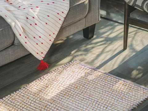 A patterned rug beside a sofa in sunlight.