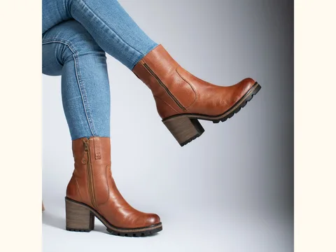 Brown leather ankle boots with side zippers worn with blue jeans.