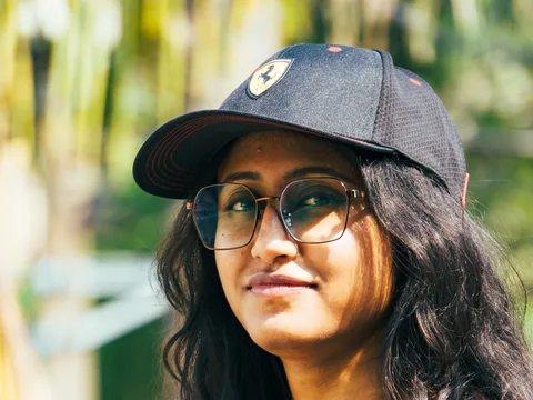 A dark baseball cap worn with a rust-colored casual shirt.