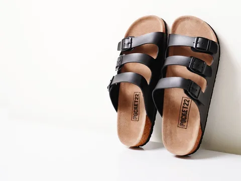 Black three-strap flat sandals with buckles and brown footbeds.