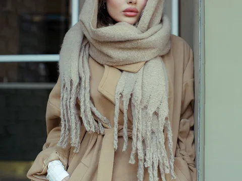 A neutral scarf worn with a beige coat.
