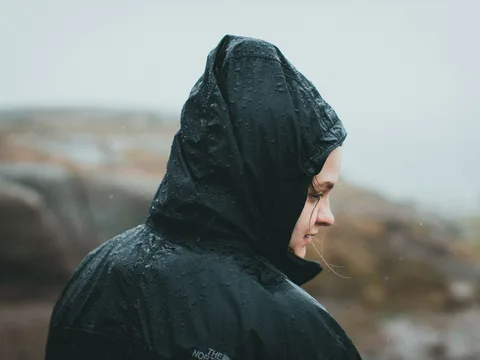 A woman wearing a hooded rain jacket outdoors.